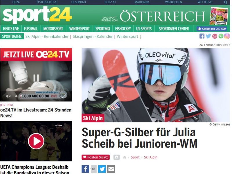 Das Bild zeigt Julia Scheib mit Helm und Skibrille mit ihrem Ski im Vordergrund.